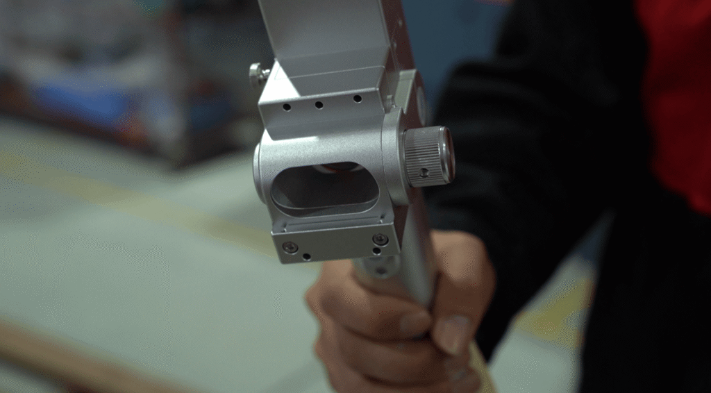 Operator using Baison hand-held laser welding gun on metal sheet.