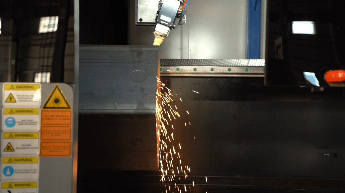 Laser cutting head processing a metal beam with bright sparks flying