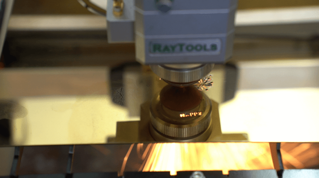 RayTools laser head cutting metal sheet with sparks.