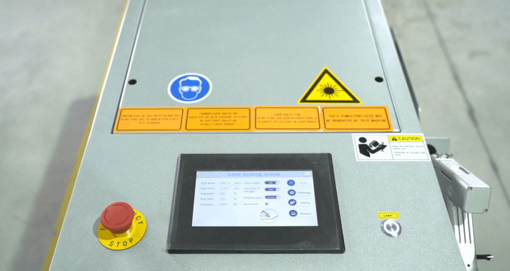 Bedienfeld der Laserschweißanlage mit Touchscreen-Oberfläche, Not-Aus-Taste und Lasersicherheits-Warnhinweisen