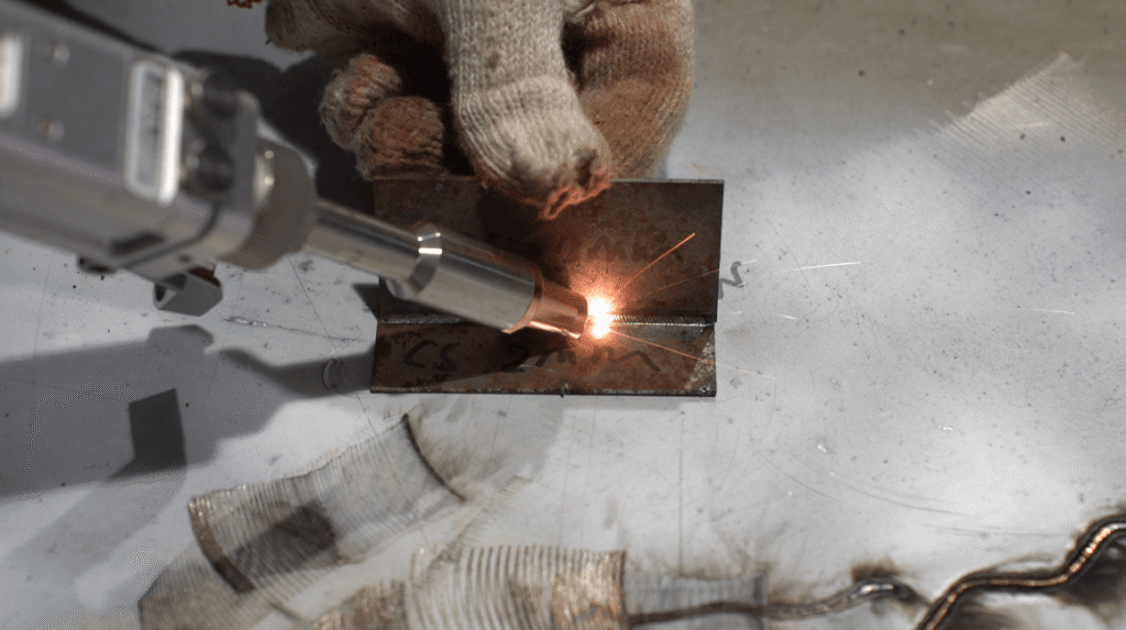Handheld laser welder creating weld on rusty carbon steel 