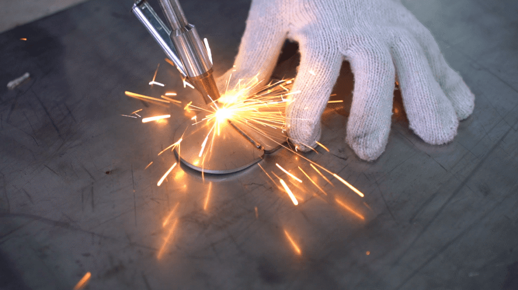 Close-up of wobble laser welding gun joining steel plates.