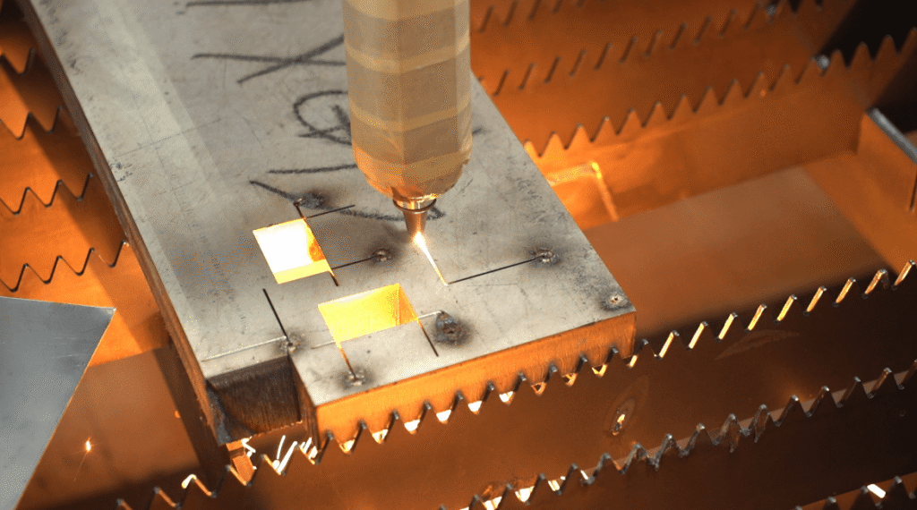 Laser cutting machine cutting square holes in a thick steel plate.
