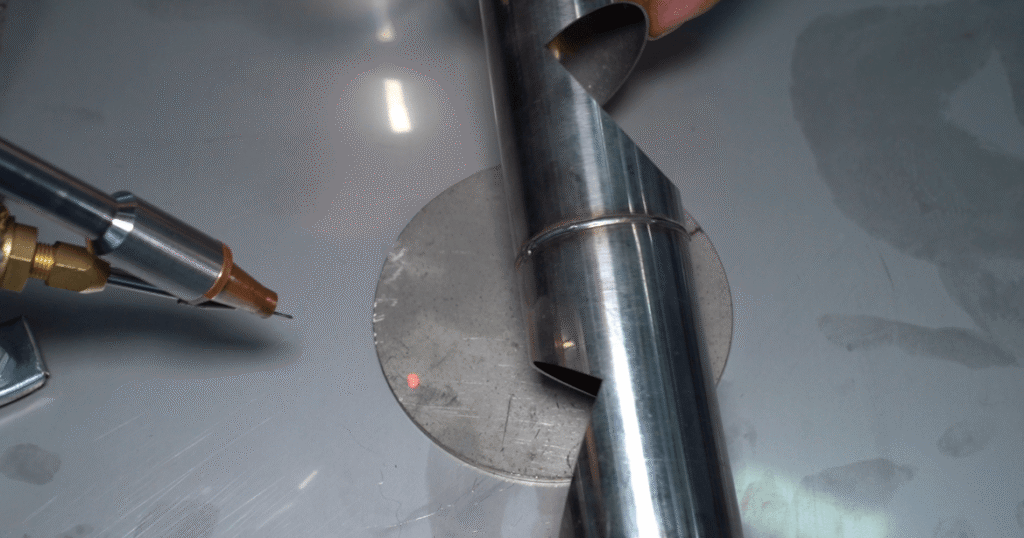 Precision laser welding nozzle aligning with a cylindrical metal part.