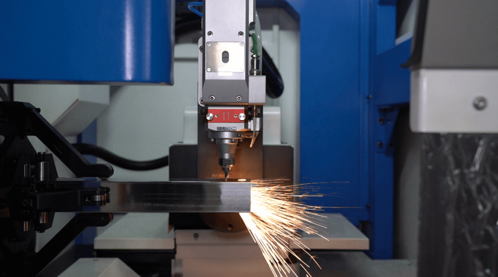 Gros plan sur un laser à fibre découpant des étincelles sur un tube robuste.