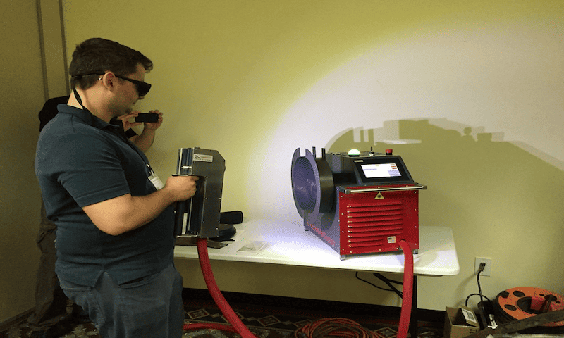Worker using handheld laser cleaning machine. 