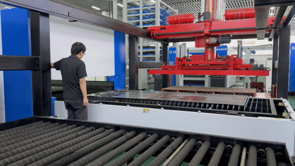 Operator standing by a large Baison laser cutting machine.