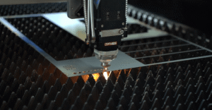 Nahaufnahme eines Laserkopfes, der mit Funken Metalllöcher schneidet.