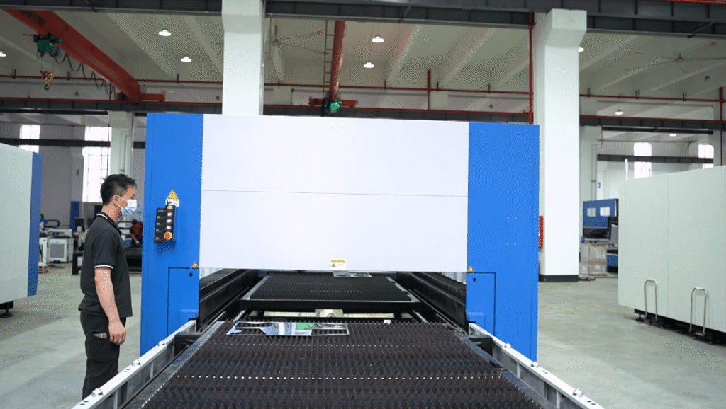 Worker operating a large blue and white laser machine.