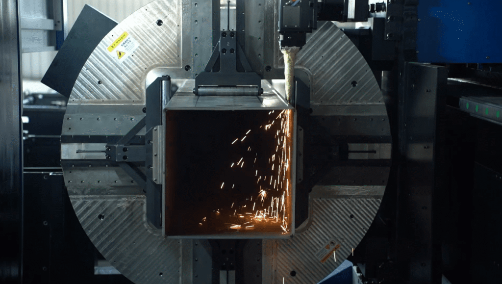 Découpe laser d'un tube d'acier carré avec étincelles.