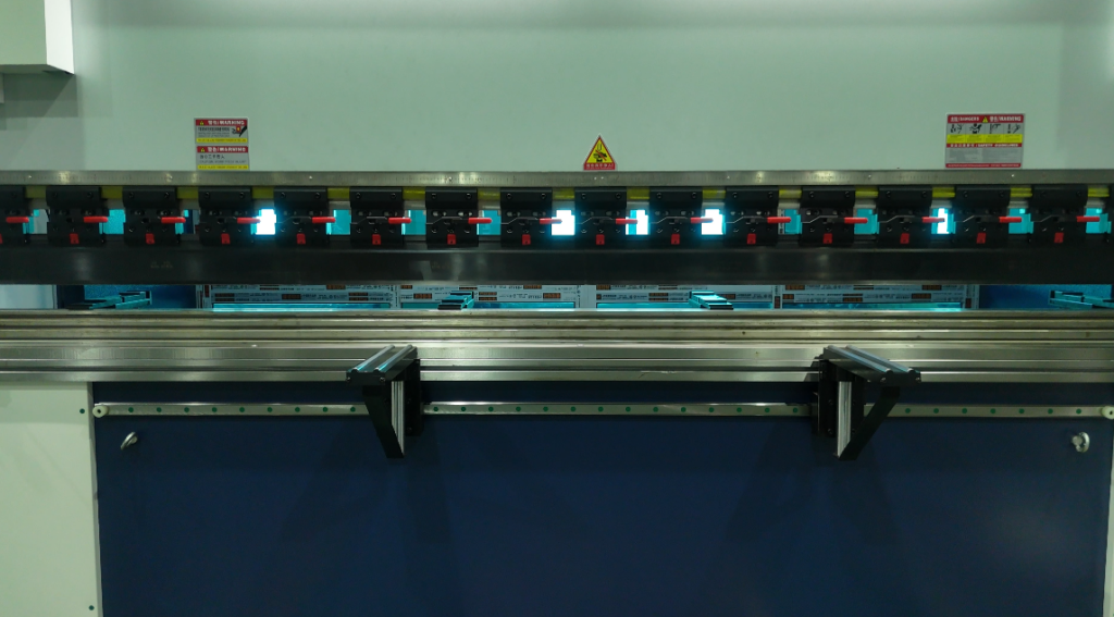 Primer plano de los moldes y el tope trasero de la máquina dobladora CNC.