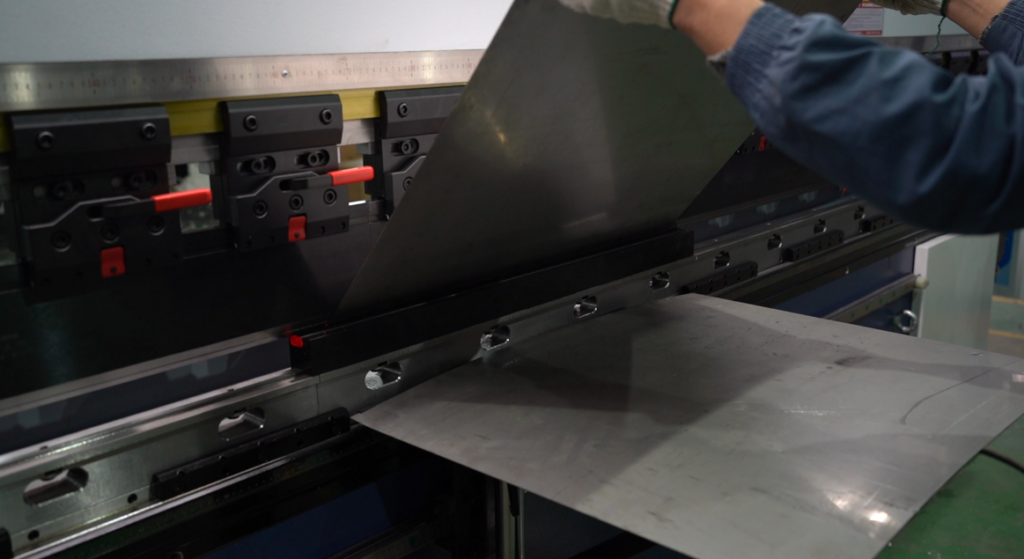 Worker feeding metal sheet into bending machine
