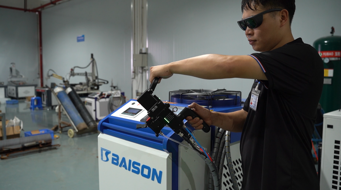 Ein Arbeiter bedient in einer Werkstatt eine Baison-Handlaserreinigungsmaschine.