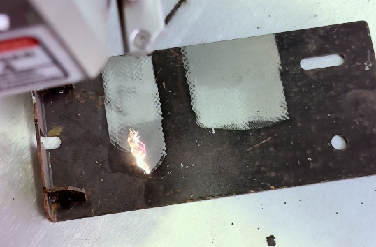 Baison laser cleaning on metal plate, showing cleaned and uncleaned areas