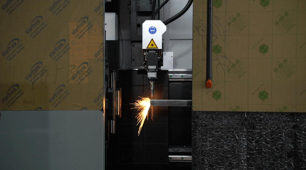 Laser head cutting square steel tube with sparks flying sideways.