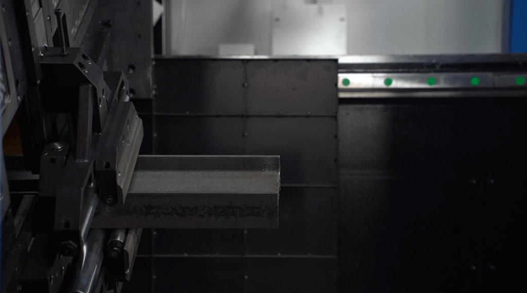 Close-up of heavy structural channel steel clamped inside the machine.