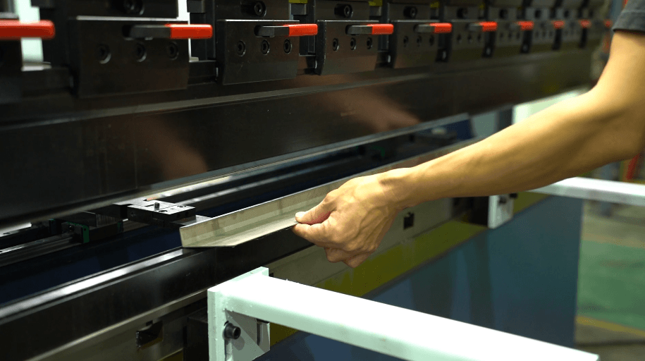 Worker operating CNC press brake to bend metal sheet