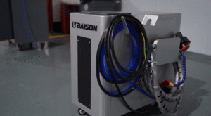 Baison suitcase pulsed laser cleaner with cables on a workshop floor.