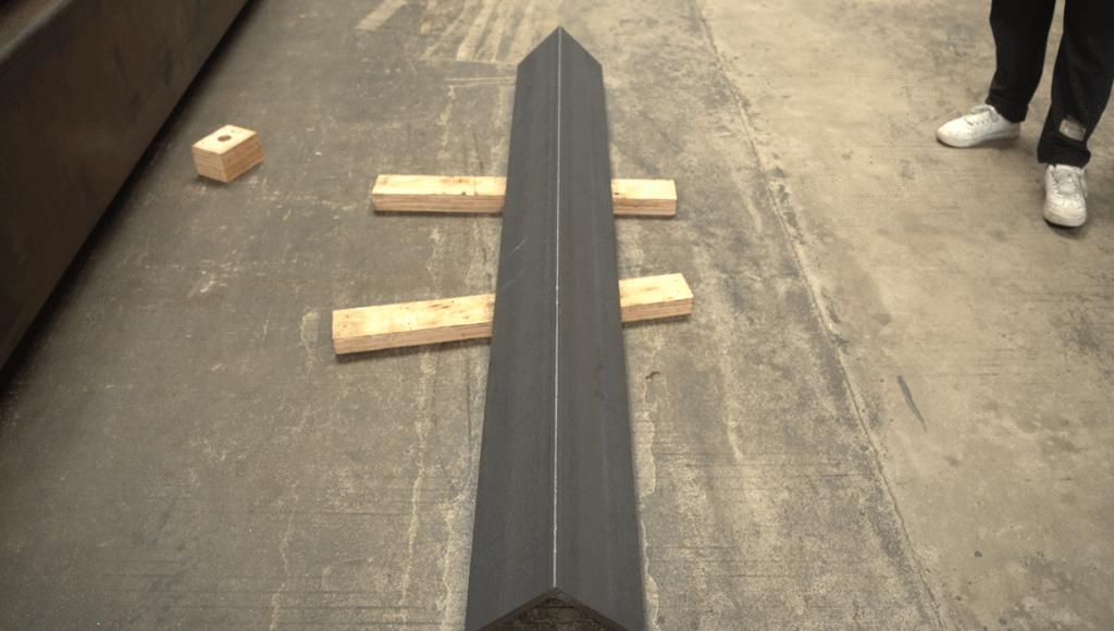Long rusty metal angle bar on wooden blocks.