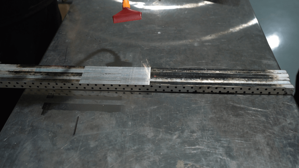 Laser cleaning process stripping oxide layers from a metal bar.