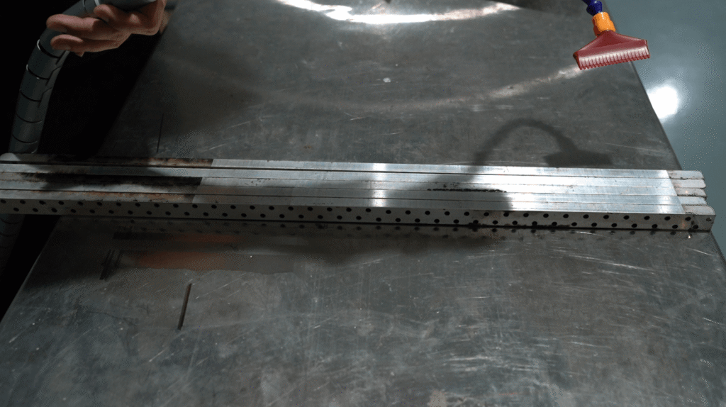 Handheld laser cleaning head removing contaminants from metal