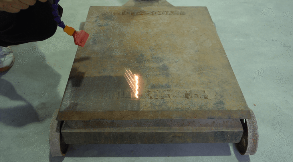 Handheld laser rust removal on a large iron plate.