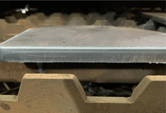 Thick steel plate edge showing heavy dross from plasma cutting process